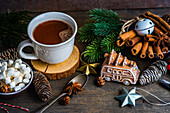 From above mug with hot chocolate and mini marshmallows with spices on background with christmas decorations