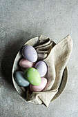 From above gray concrete table setting with colored eggs on ceramic bowl for festive dinner