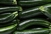 Top view of stacks of green thin zucchini squashes at farmers market as background