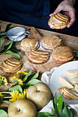 High angle of anonymous person taking delicious apple tartlet from table in kitchen at home