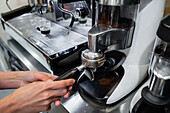 From above of crop unrecognizable barista with portafilter preparing aromatic drink in coffee machine in cafe