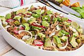 Cuban bowl with pulled meat and chopped avocado with jalapeno and radish and lime served in white ceramic bowl