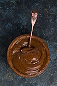 Top view of a dulce de leche in brown bowl mixed with a spoon in black background