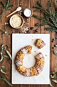 Overhead view of tasty three kings cake decorated with almond petals and coconut flakes among Eucalyptus and fir sprigs