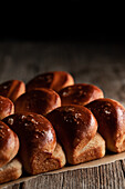 From above baked tasty soft dinner rolls on tray placed on wooden surface in dim light