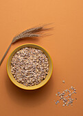 From above oats in bowl on light table brown background