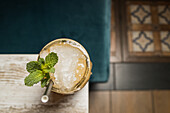 Von oben auf Tiki-Becher mit kaltem Alkoholgetränk mit Strohhalm, serviert mit Eis und dekoriert mit frischem Kraut auf unscharfem Hintergrund