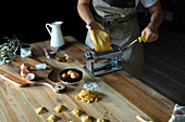 Unrecognizable person preparing raviolis and pasta at home. She is using a pasta machine