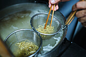 Stock photo of unrecognized chef in japanese restaurant preparing noddles soup.
