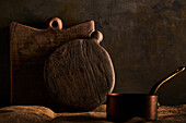 Handmade wooden chopping board of brown color placed on rustic table near pot in kitchen