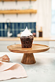 Chocolate cupcake with sweet whipped cream on cake stand at home