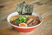 Stockfoto von leckerer Ramen-Suppe mit gekochtem Ei und Fleisch in einem japanischen Restaurant, bereit zum Servieren