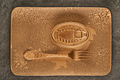 Top view of gold fork placed near sealed canned food on rectangular copper tray