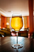 Glass of beer in a wooden table in a pub against blurred background