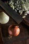 Von oben geschnittene Zwiebelstücke neben dem Messer auf dem Holztisch in der Küche