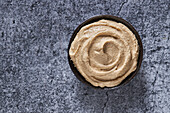 Top view of fresh hummus served in bowl on cracked gray marble table in kitchen