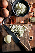 Top view of rustic bowl with pieces of cut onion placed near knife on lumber table in kitchen