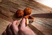 Von oben der Ernte anonymen Koch Schneiden knusprig frittierten Käse Ball auf hölzernen Schneidebrett