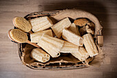 Top view of wooden basket placed on floor filled with brushes and zero waste natural luffa sponges