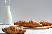 Delicious croissants and bottle of milk placed on table for breakfast in kitchen