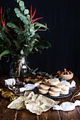 Pile of appetizing sweet shortbread cookies with hazelnuts served on plate on wooden table with festive wrapping paper and ribbons for Christmas celebration