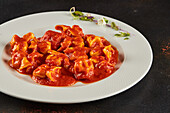 High angle of delicious meat ravioli with ragu bolognese sauce served on plate with sprouts on dark table in restaurant