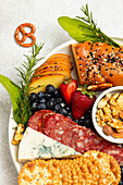 Top view of tasty charcuterie plate with assorted cheese and nuts served with ripe strawberries on table in light kitchen