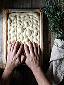 Top view of faceless person preparing raw dough for bread placed on baking paper on table