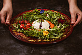 Yummy burrata cheese on cold tomato cream with arugula leaves and cherry tomatoes with truffles and peanuts