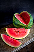 High angle of slices of ripe sweet watermelon placed on wooden table on dark background