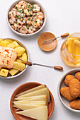 From above assorted traditional spanish tapas served on bowls on white table background