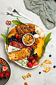 Top view of tasty charcuterie plate with assorted cheese and mushrooms served with ripe strawberries on table in light kitchen