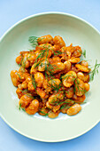 From above of delicious traditional Greek giant naked beans in tomato sauce served in plate on gray background in kitchen