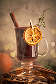 Gluhwein or christmas punch mulled wine server on a glass mug with dried orange slices