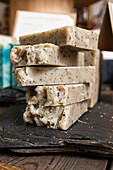 Many bars of beige handmade soap for hygiene placed on wooden board in workshop