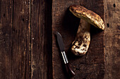 Draufsicht auf roh geschnittene Steinpilze (Boletus edulis) auf rustikalem Holzschneidebrett während des Kochvorgangs