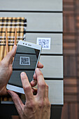 Ernte von oben, nicht erkennbarer Mann, der ein Smartphone benutzt und den QR-Code der Speisekarte eines Restaurants scannt