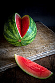 Hoher Winkel von Scheiben reifer süßer Wassermelone auf Holztisch vor dunklem Hintergrund