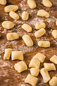 From above top view of uncooked gnocchi placed in rows on lumber table during lunch preparation at home