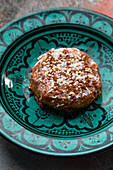 From above of sweet tasty cake decorated with nuts and cocoa and sugar powder on plate in oriental style