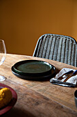 From above of wooden table with ceramic plates and cutlery on napkin near wineglass in restaurant