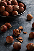 From above bunch of ripe hazelnuts in bowl and shells on marble table