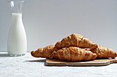 Delicious croissants and bottle of milk placed on table for breakfast in kitchen