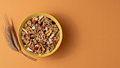 Von oben knuspriges Müsli mit getrockneten Früchten in Schale auf hellem Tisch mit braunem Hintergrund