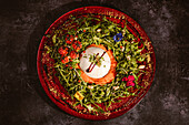 Overhead view of yummy burrata cheese on cold tomato cream with arugula leaves and cherry tomatoes with truffles and peanuts