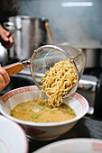 Stockfoto eines unbekannten Kochs in einem japanischen Restaurant, der Nudelsuppe serviert