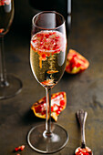 Still life composition of champagne cocktail with pomegranate on a rustic surface