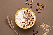 From above yoghurt served with oats and dried nuts on brown background