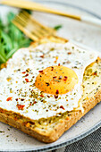 Toast with eggs and cheese and rocket lettuce served on plate on table background