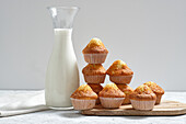 Yummy homemade freshly baked sweet muffins in paper cups arranged on table with glass jar of fresh milk